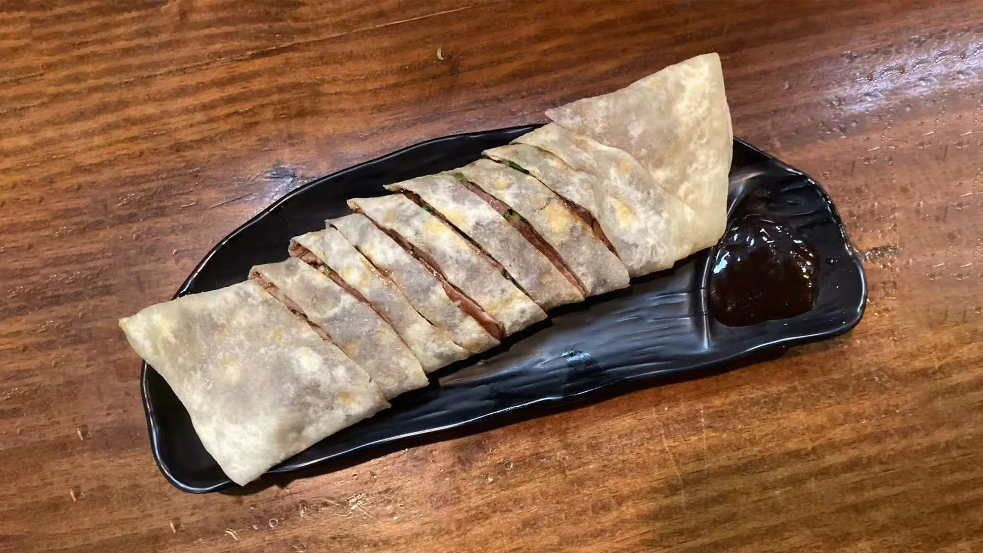 Sliced rolled beef served with a small plate of dipping sauce at Noodle Man，a Chinese Restaurant in Virginia Beach