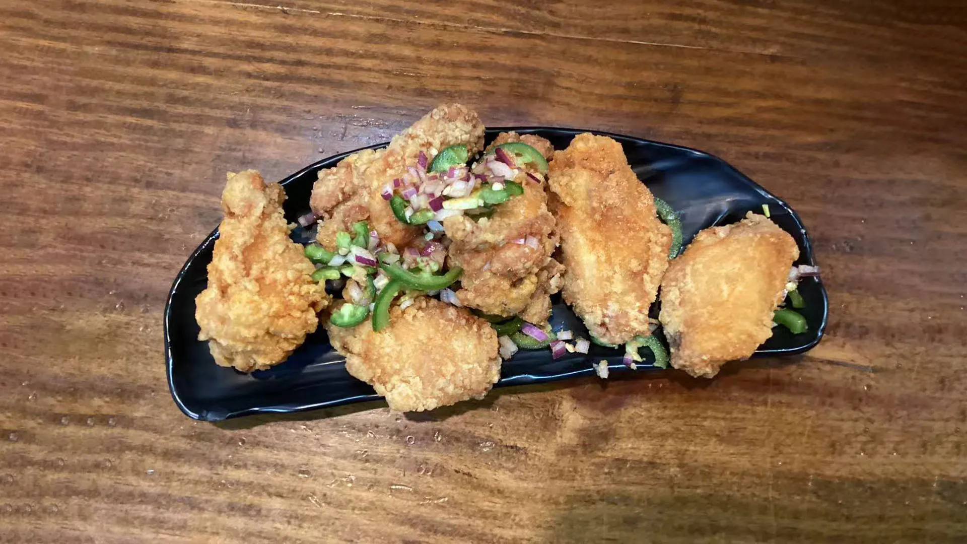 Six crispy salt and spicy chicken wings garnished with fresh onions at Noodle Man，a Chinese Restaurant in Virginia Beach