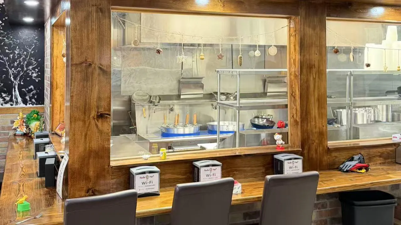 Open kitchen viewing window with wooden counter and dining seats at Noodle Man，a Chinese Restaurant in Virginia Beach