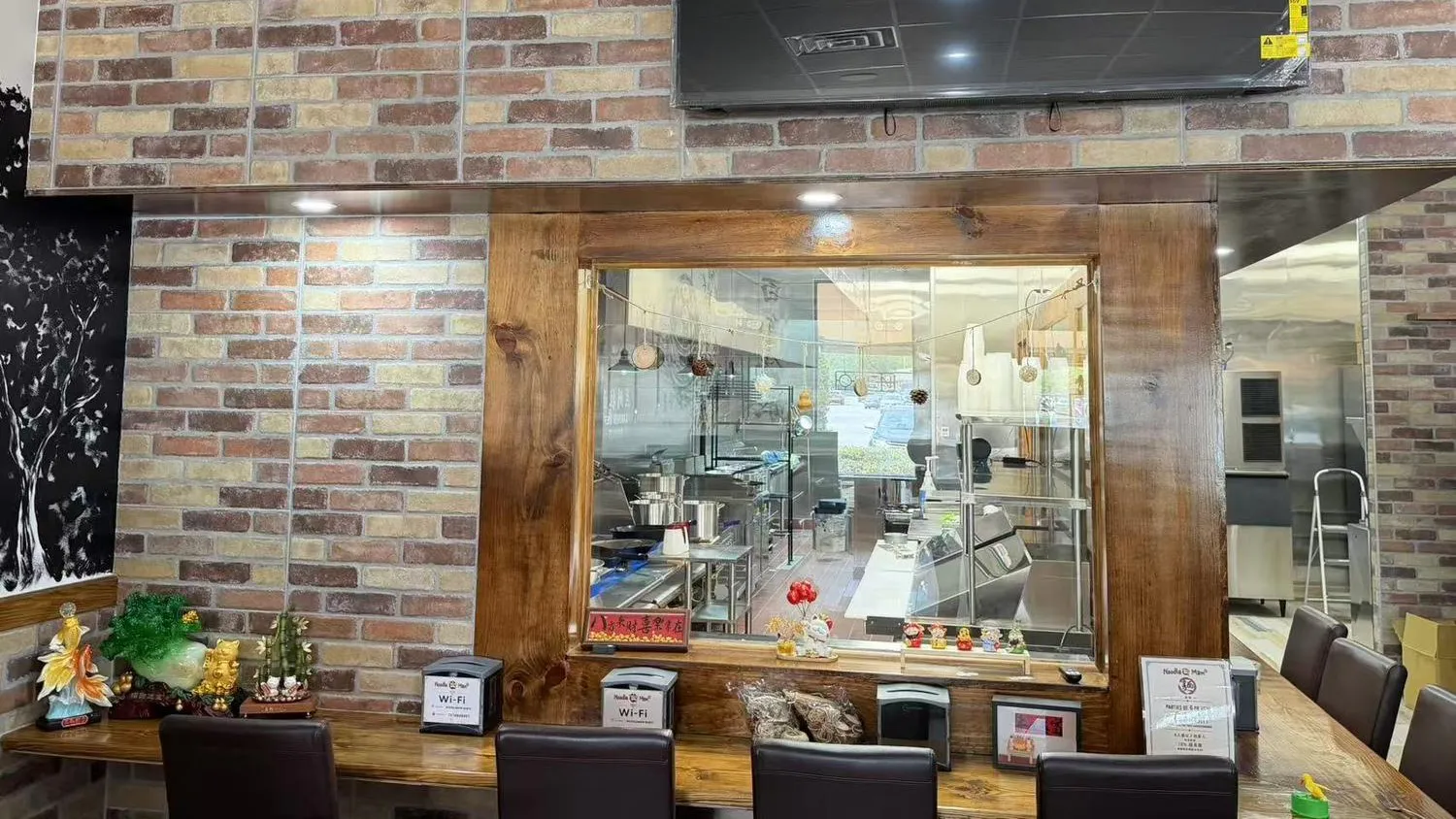 Brick wall open kitchen window with decorative ornaments and bar seats at Noodle Man，a Chinese Restaurant in Virginia Beach